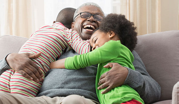 Grandpa hugging his grandkids confident about his retirement and estate gameplan through BOK. 